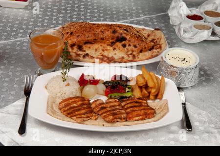 Le kebab de shish est de la viande de poulet. Il y a du kebab de shish, du pain pita et du jus de fruits sur la table à manger. Banque D'Images