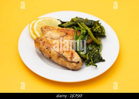 Caviar grillé avec des légumes verts et du citron frais sur une petite assiette blanche sur papier jaune. Banque D'Images