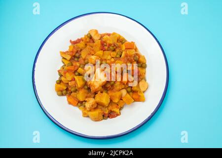 ragoût de légumes dans un plat blanc sur du bleu Banque D'Images