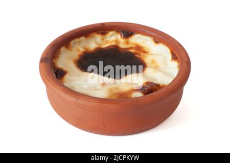 Vue sur le profil de délicieux pudding au riz cuit, dessert laiteux traditionnel connu sous le nom de « sutlac » turc en cocotte en faïence, isolée sur blanc Banque D'Images