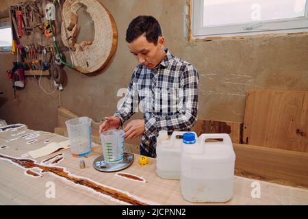 Menuisier préparant de la résine époxy. Procédé de fabrication d'une table de résine et de bois d'artisanat. Banque D'Images