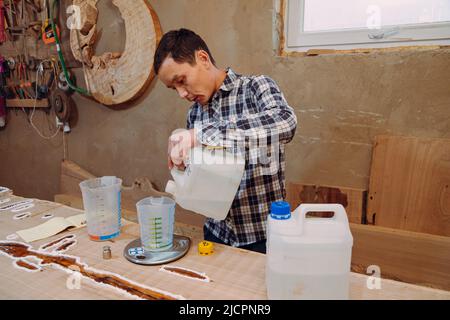 Menuisier préparant de la résine époxy. Procédé de fabrication d'une table de résine et de bois d'artisanat. Banque D'Images