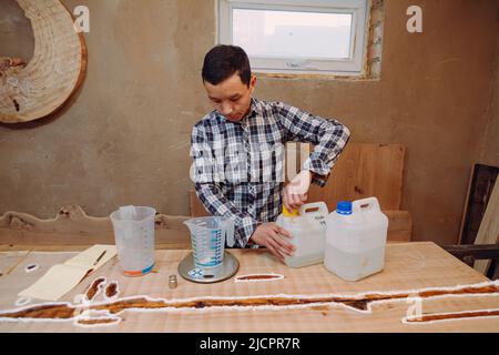 Menuisier préparant de la résine époxy. Procédé de fabrication d'une table de résine et de bois d'artisanat. Banque D'Images