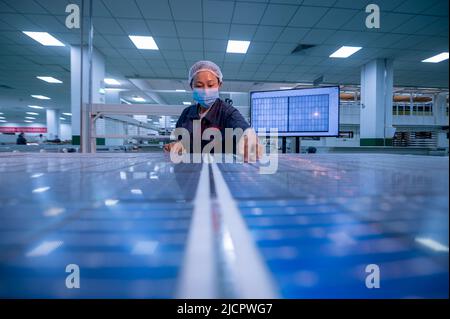 YANGZHONG, CHINE - 15 JUIN 2022 - Un travailleur inspecte les panneaux photovoltaïques finis dans un atelier de production à Yangzhong, province de Jiangsu, Banque D'Images