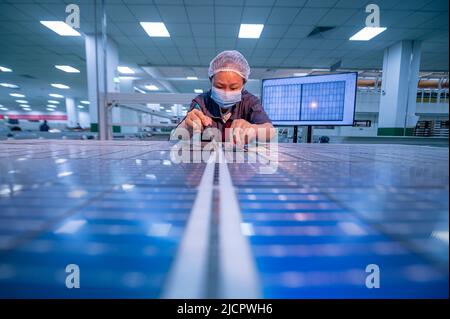 YANGZHONG, CHINE - 15 JUIN 2022 - Un travailleur inspecte les panneaux photovoltaïques finis dans un atelier de production à Yangzhong, province de Jiangsu, Banque D'Images