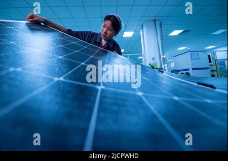 YANGZHONG, CHINE - 15 JUIN 2022 - Un travailleur inspecte les panneaux photovoltaïques finis dans un atelier de production à Yangzhong, province de Jiangsu, Banque D'Images