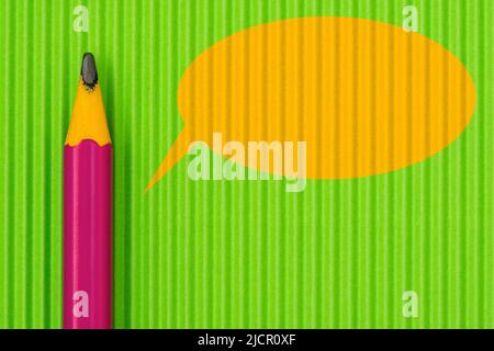 Crayon violet sur fond de papier vert avec bulle de dialogue jaune Banque D'Images