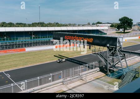 Courses de voitures d'époque le long de Hamilton Straight. Sous le panneau de signalisation de la machine à grande vitesse, un jour ensoleillé au circuit de Silverstone, Northamptonshire, Royaume-Uni. Banque D'Images