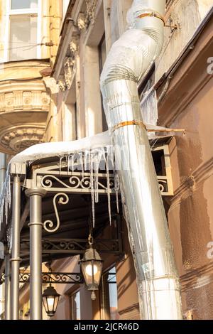 Des glaçons très pointus et de la neige fondue pendent des avant--toits de toit et de descente. Photo verticale. Banque D'Images