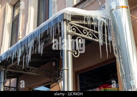 Des glaçons très pointus et de la neige fondue pendent des avant--toits de toit et de descente. Journée ensoleillée et glacial. Banque D'Images