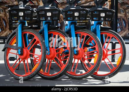 Quatre vélos de location alignés avec des jantes rouges sur le trottoir à Rome, Italie. Banque D'Images