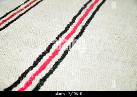 Tapis en coton blanc à rayures noires et rouges. Arrière-plan de texture. Moquette de plancher en gros plan Banque D'Images