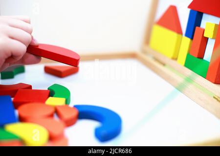 l'enfant joue à un jeu éducatif magnétique en bois. l'enfant joue avec un jouet sur fond blanc. l'enfant joue avec un constructeur Banque D'Images