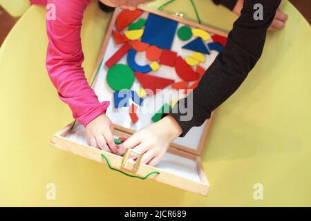 les enfants jouent ensemble à des jeux éducatifs magnétiques en bois. les enfants jouent en mosaïque. vue du dessus. les enfants jouent avec un constructeur Banque D'Images