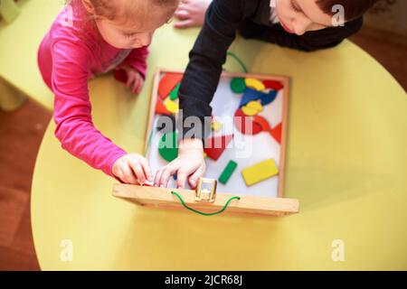 les enfants jouent ensemble à des jeux éducatifs magnétiques en bois. les enfants jouent en mosaïque. vue du dessus. les enfants jouent avec un constructeur Banque D'Images