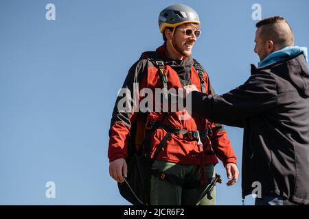 Homme aidant le pilote de parapente à se préparer au vol. Banque D'Images