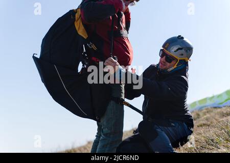 Homme aidant le pilote de parapente à se préparer au vol. Banque D'Images