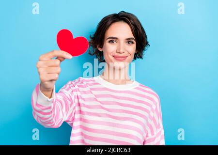 Portrait de jolie gaie courte coupe de cheveux femelle vous donner petite surprise carte de papier rouge isolée sur fond bleu de couleur Banque D'Images