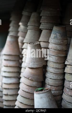 Gros plan des piles de pots de fleurs de terre cuite anciens et altérés dans le hangar de jardinage Banque D'Images