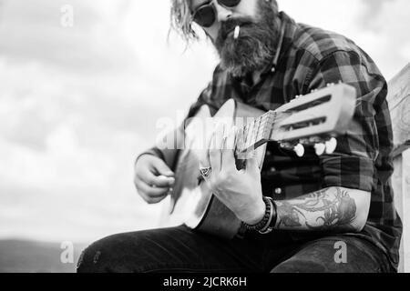 homme barbu dans une chanson de chant de chemise à damier. musicien interprète de musique. instrument de cordes musicales. guitariste mâle charismatique mature. gars avec barbe et Banque D'Images