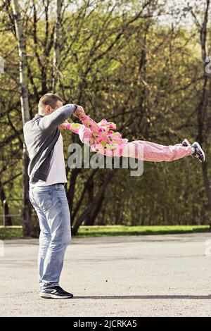 Papa joue avec sa fille dans l'arrière-cour. Il se déroule autour de lui-même. Famille, papa joue avec sa fille le week-end. Banque D'Images