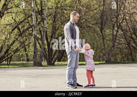 Papa joue avec ses filles dans le parc. Faire tourner une fille autour. Famille. Banque D'Images