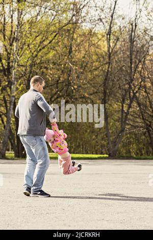 Papa joue avec sa fille dans l'arrière-cour. Il se déroule autour de lui-même. Famille, papa joue avec sa fille le week-end. Banque D'Images