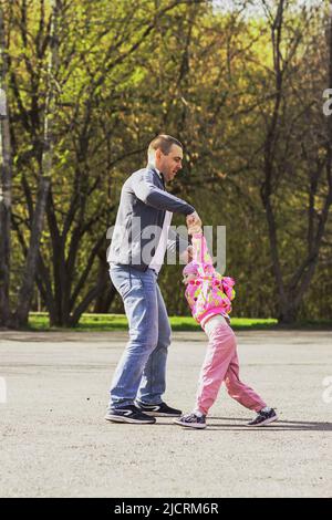 Papa joue avec sa fille dans l'arrière-cour. Il se déroule autour de lui-même. Famille, papa joue avec sa fille le week-end. Banque D'Images