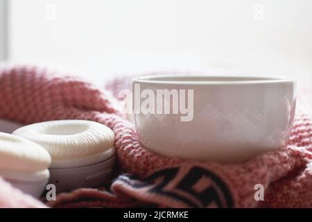 Agréable matin d'hiver à la maison. Thé ou café chaud, pull en maille et écouteurs près de la fenêtre. Concept de style de vie et de musique Banque D'Images