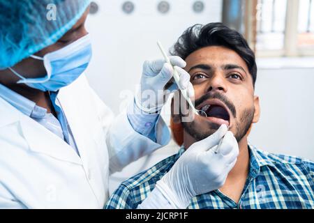 gros plan du dentiste avec des gants chirurgicaux vérifiant les dents du patient à l'hôpital ou à la clinique - concept de soins buccaux, traitement des maux de dents et Banque D'Images