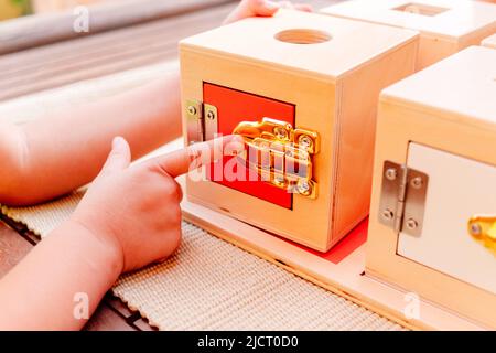 Petite fille joue avec un matériel éducatif montessori pour ouvrir et fermer des boîtes en bois. Banque D'Images