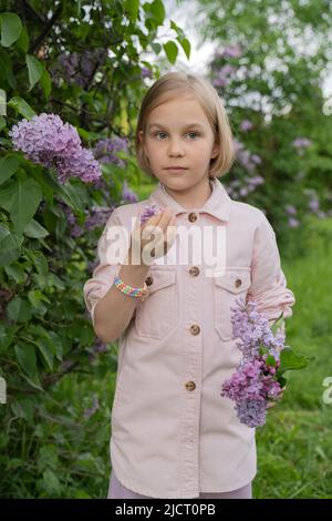 Portrait d'une fille de 8 ans dans un parc avec des lilas. Banque D'Images