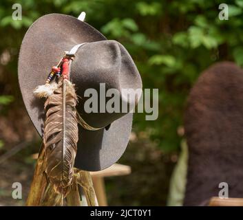 Chapeau gris avec perles colorées et une longue plume d'oiseau est accroché sur un poteau sur un fond flou Banque D'Images