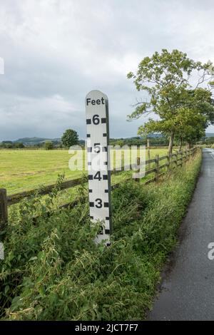 Jauge de profondeur d'eau d'inondation en bord de route (indiquant la profondeur d'eau des conducteurs dans la région) sur la plaine d'inondation de la rivière aire près de Skipton, dans le North Yorkshire, au Royaume-Uni. Banque D'Images