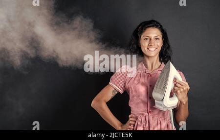 femme heureuse. femme vintage repassant des vêtements. ménage. petite fille utilise un fer vapeur. appareil pour la maison. femme de ménage repassant. heureuse et souriante Banque D'Images