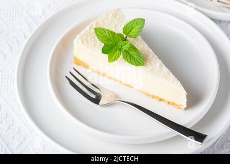 Cheesecake dans une assiette sur une table blanche Banque D'Images