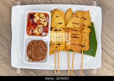 Vue en hauteur de poulet satay sur des bâtonnets, servi avec de la salsa, de la sauce trempée et prêt à manger. Banque D'Images