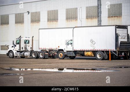 Semi-camion à cabine de jour avec semi-remorque de camionnette sèche et petit camion de plate-forme avec remorque à caisse debout sur le parking industriel à côté du buil d'entrepôt Banque D'Images