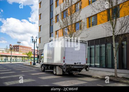 Petite plate-forme au-dessus de la cabine semi-camion blanc avec remorque à caisse longue pour la livraison commerciale locale dans la ville urbaine avec plusieurs étages construction d'appartements résidentiels Banque D'Images