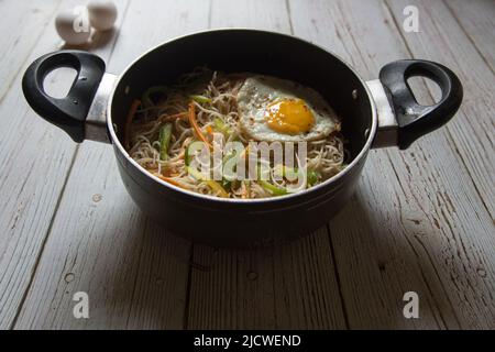 Faites cuire les nouilles frites dans une casserole sur fond. Gros plan, mise au point sélective. Banque D'Images