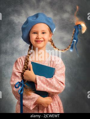 Portrait rapproché d'une fillette heureuse avec deux tresses volantes sur fond gris avec livre Banque D'Images