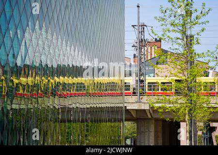Reflet d'un train de banlieue en mouvement dans la façade vitrée du Futurium Berlin. Banque D'Images