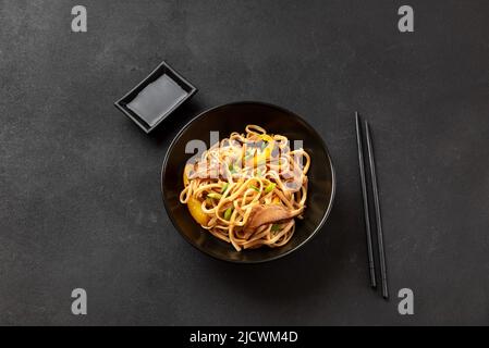 Nouilles Udon dans une assiette noire sur fond sombre. Cuisine asiatique Banque D'Images