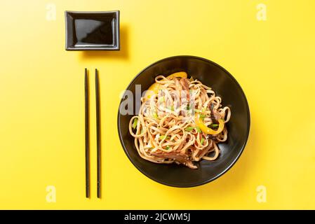 Nouilles udon asiatiques avec sauce sur fond jaune Banque D'Images