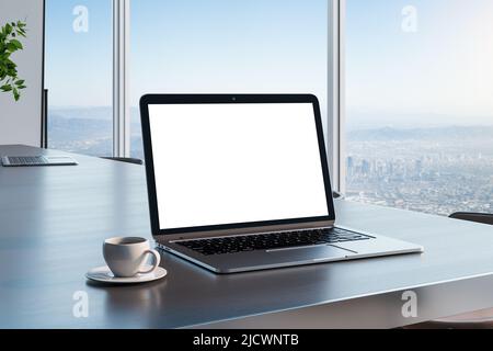 Écran blanc vierge pour ordinateur portable avec espace pour le texte sur une table en bois sombre avec une tasse de café dans une pièce ensoleillée et vue sur la ville depuis un mur en verre. 3D réf Banque D'Images
