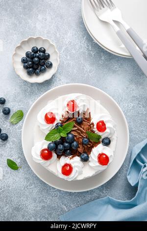 Gâteau au chocolat, cheesecake blanc décoré de bleuets, de cerises, de chocolat brun et de crème fouettée Banque D'Images