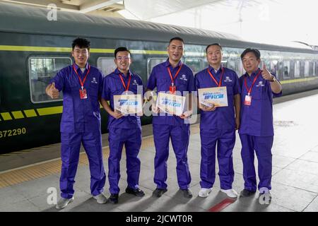 (220616) -- HOTAN, 16 juin 2022 (Xinhua) -- les membres du personnel de China Railway 11th Bureau Group Co. Ltd. Posent pour une photo de groupe devant le premier train du chemin de fer Hotan-Ruoqiang à la gare de Hotan, dans le nord-ouest de la Chine, la région autonome de Xinjiang Uygur, au 16 juin 2022. La dernière section d'une ligne de 2 712 km autour du plus grand désert de Chine, le Taklimakan, dans la région autonome du Xinjiang, la plus au nord-ouest du pays, a été mise en service jeudi. L'ouverture de la ligne ferroviaire Holan-Ruoqiang permettra aux trains de contourner un désert pour les premiers Banque D'Images