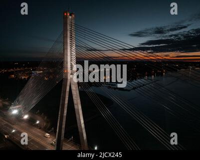 Vue panoramique aérienne du pont de Riga traversant la rivière Daugava la nuit. Banque D'Images