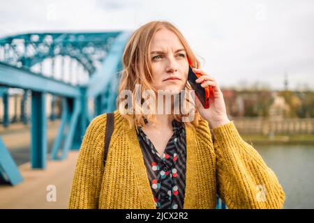 Gros plan portrait d'une femme blonde de choc, stressée et malheureuse 30s utilisant un smartphone, entend de mauvaises nouvelles à l'extérieur. Santé mentale, aide psychologique et Banque D'Images