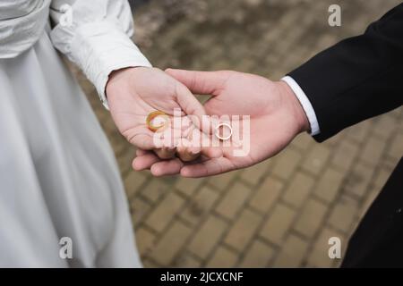 vue en grand angle du marié et de la mariée tenant les anneaux de mariage entre les mains Banque D'Images
